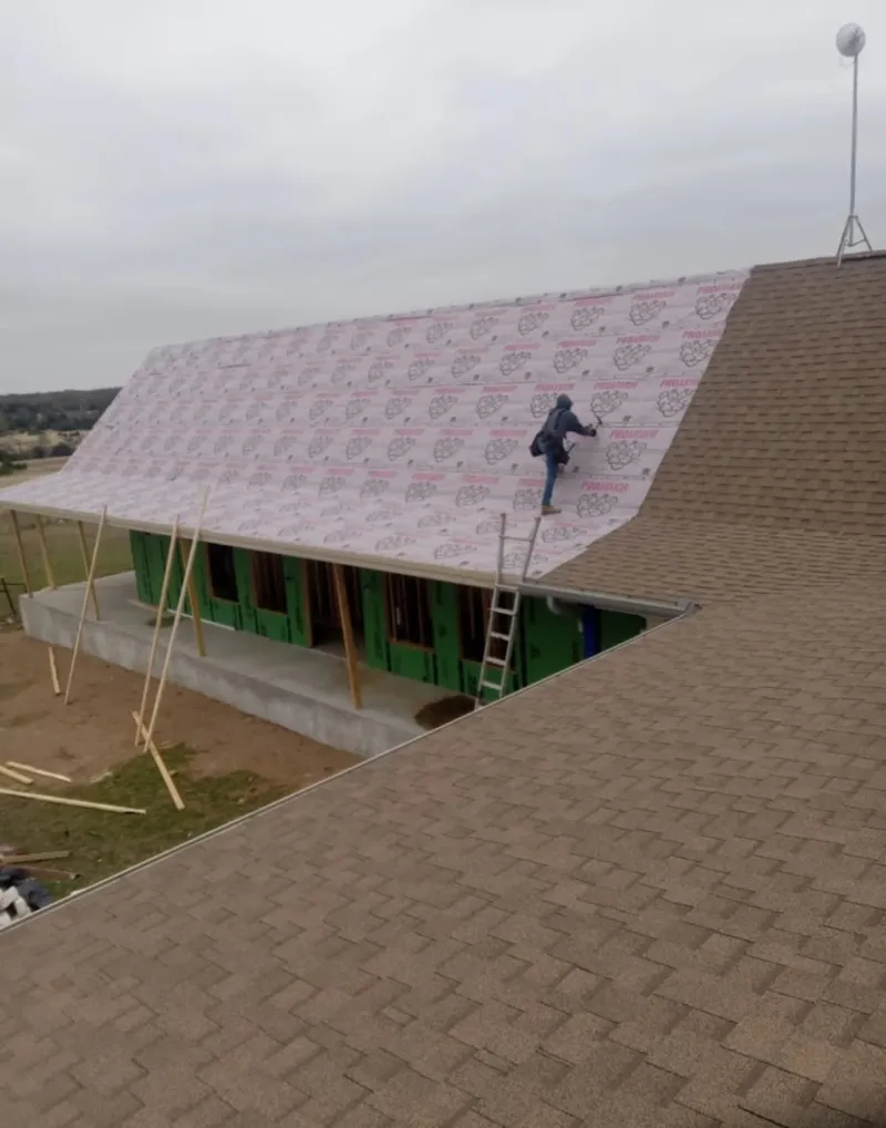 Worker preparing underlayment for a metal roof installation in Verdigris